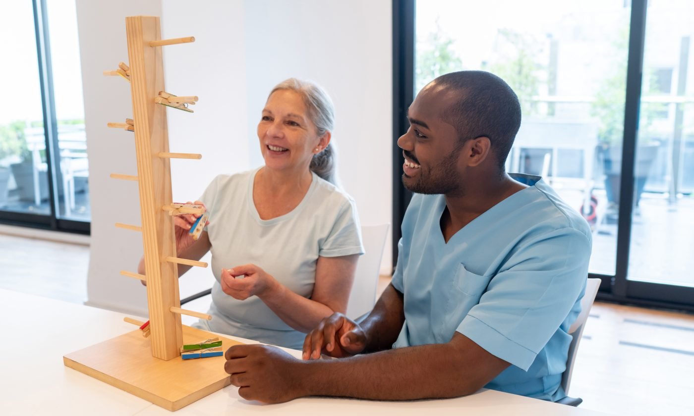 cheerful senior woman in occupational therapy with a black male patient having fun